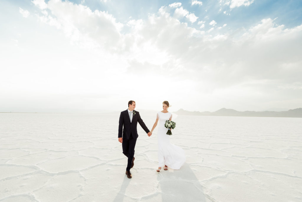 bride and groom walking and holding hands at the utah bonneville salt flats