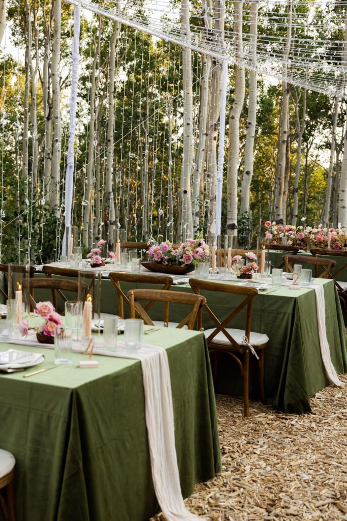 Park City floral tablescape and waterfall lighting wedding reception setup displayed in an Aspen forest.