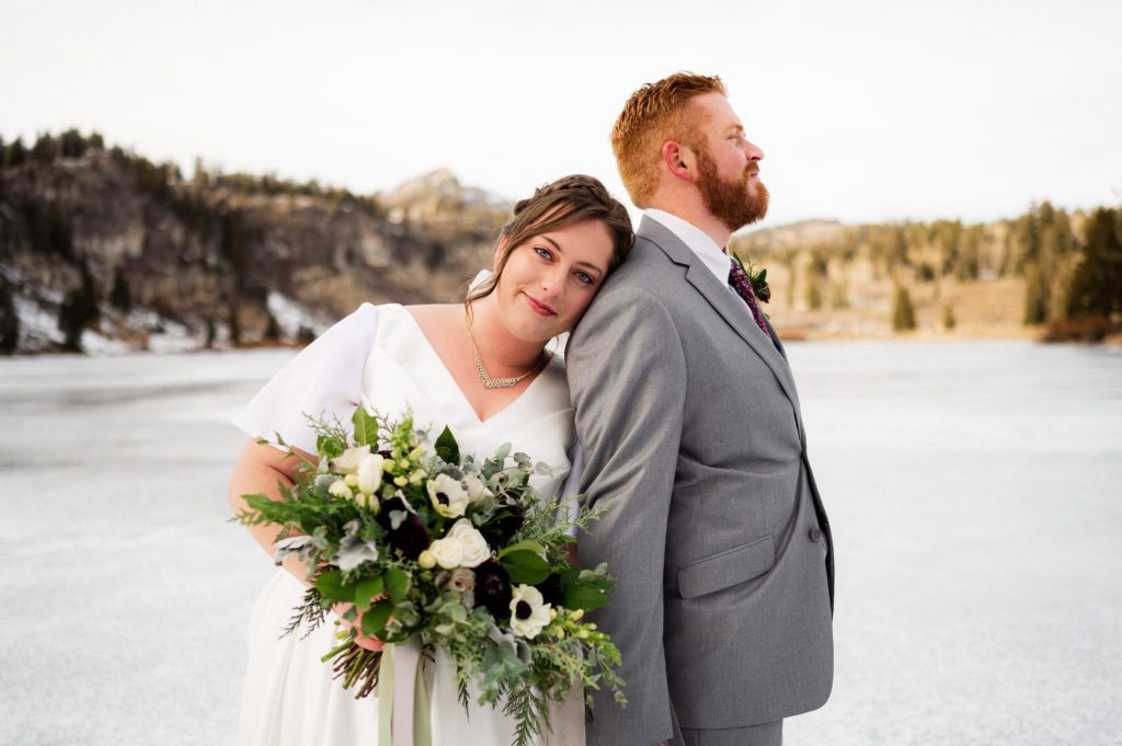 Bride leans against groom during snowy first look wedding photoshoot at Tony Grove Lake in Logan Utah.