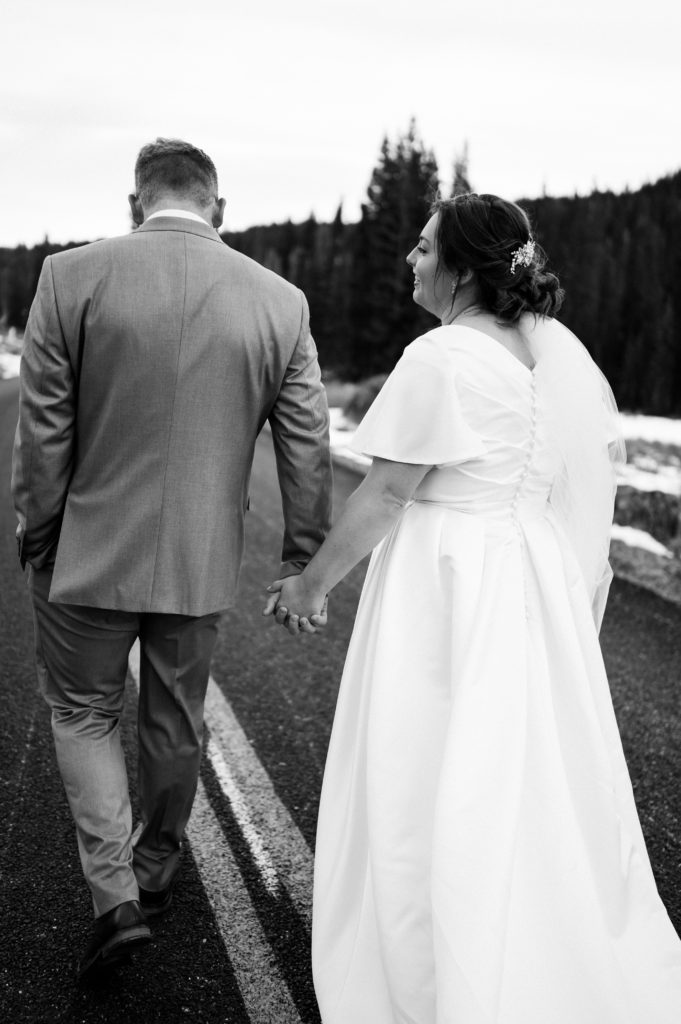 This snowy first look session took place with Logan Utah wedding photographer and videographer The Manos Photo and Film. The couple runs away with bride looking at the groom.