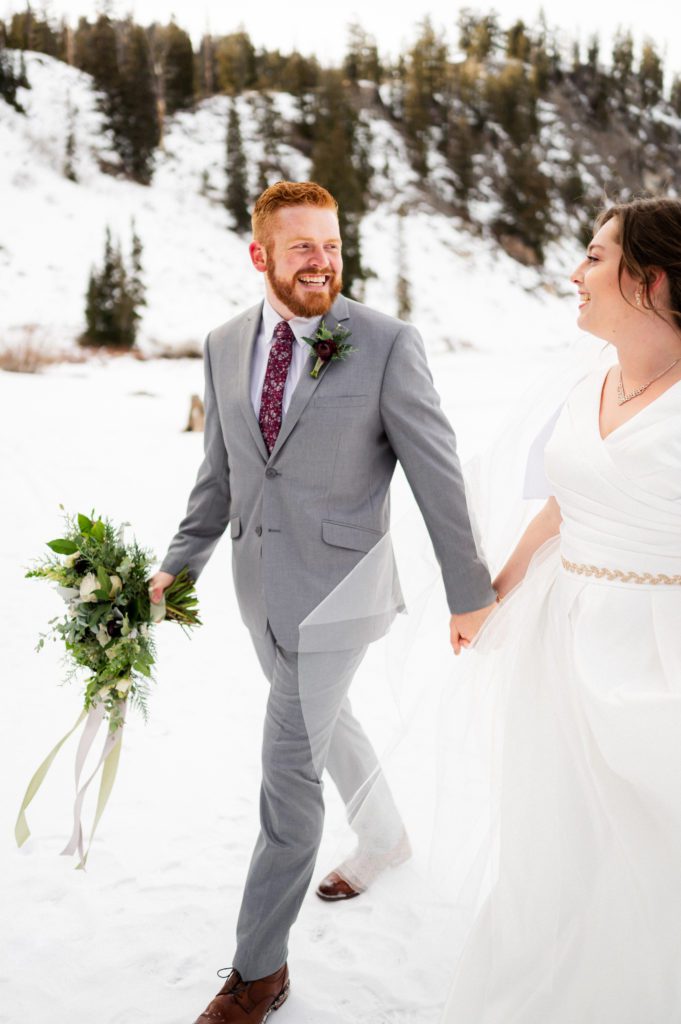 This snowy first look session took place with Logan Utah wedding photographer and videographer The Manos Photo and Film. The couple poses with hand holding and smiling at each other.
