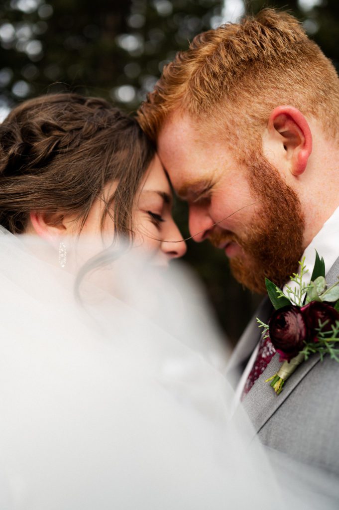 This snowy first look session took place with Logan Utah wedding photographer and videographer The Manos Photo and Film. The bride's veil swoops over the couple.