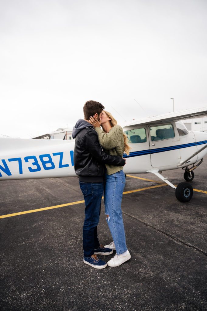 Utah engaged couple kisses after surprise airport proposal.