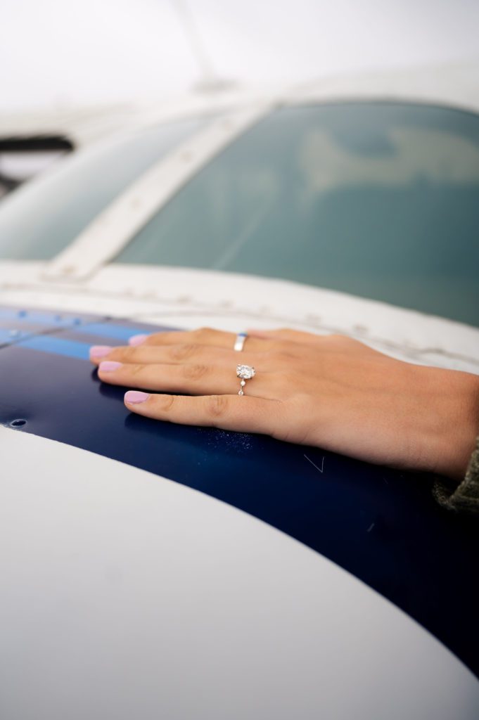 Unique wedding ring on fiance's finger at Logan airport surprise proposal.
