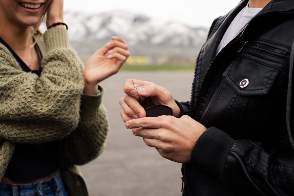 Man pulls out an engagement ring at surprise airport proposal.