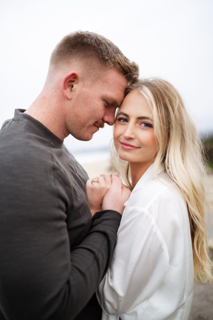 Couple snuggles up for poses during half moon bay engagements with san francisco, california wedding photographer and videographer team.
