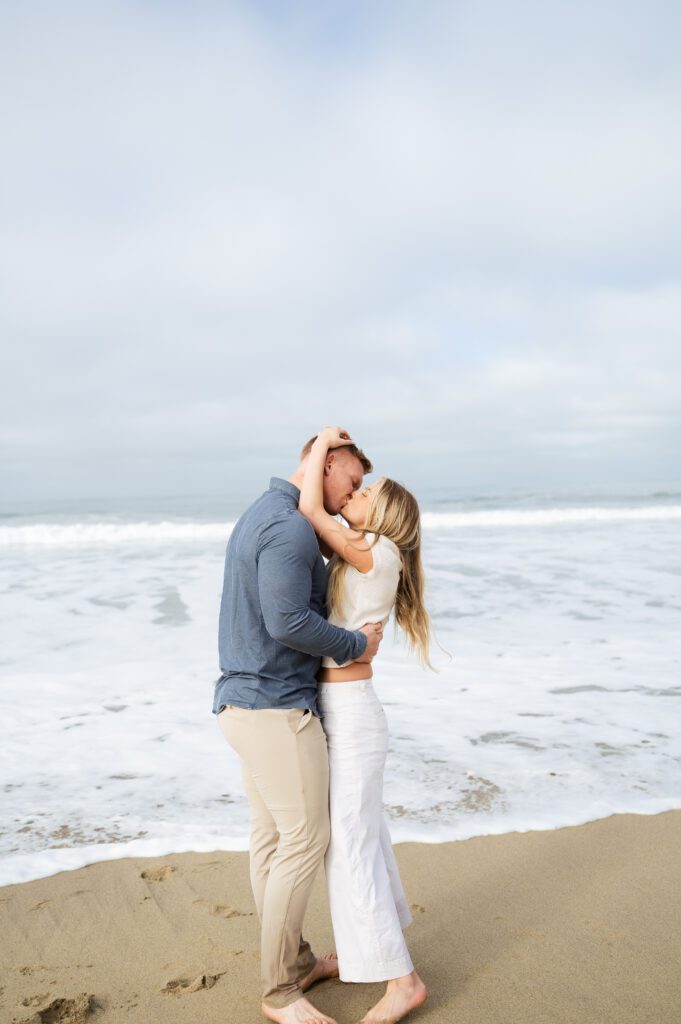 Half moon bay engagements at the beach with couple kissing