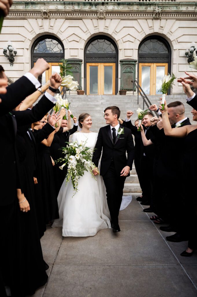 Bridal party cheers for newly married bride and groom in Syracuse New York downtown.