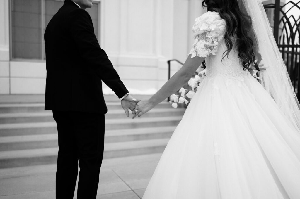 classic winter bride and groom hold hands at their high-fashion Vogue-inspired lds temple wedding