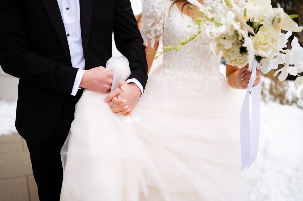 bride and groom hold hands at classic fashion winter wedding at brigham city temple