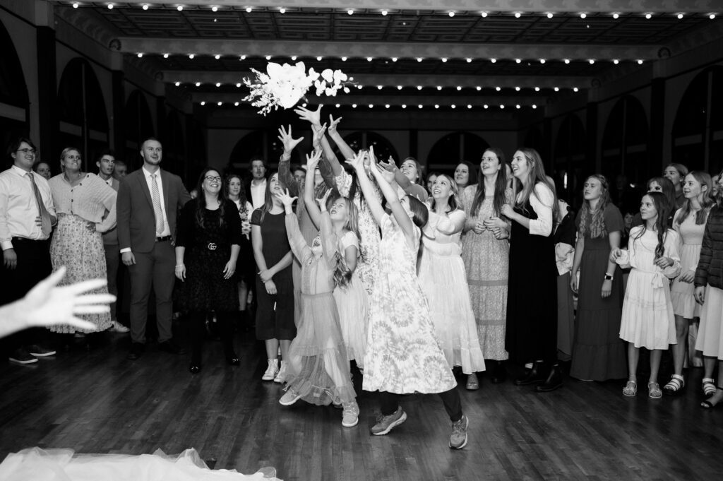 photographer captures middair bouquet toss at northern utah classic fashion winter wedding