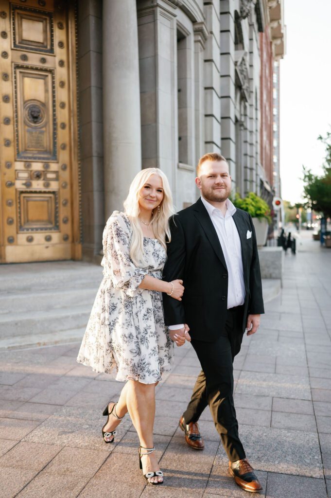 couple walking downtown salt lake city for engagements pre-wedding photoshoot gold door utah location