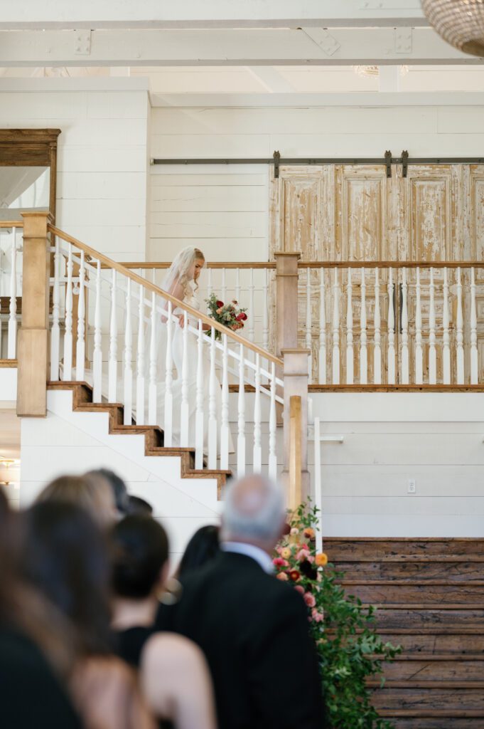wedding guests stand as bride enters, walks down the staircase at walker farms venue in lindon, utah