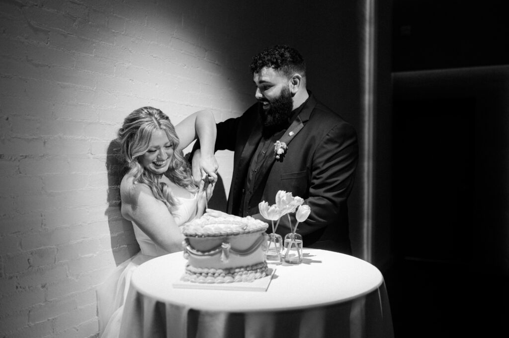 Black-and-white shot of a couple cutting their cake at their Florida wedding venue