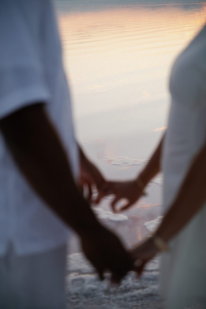 The couple holding hands during Utah pink lake engagement photo shoot