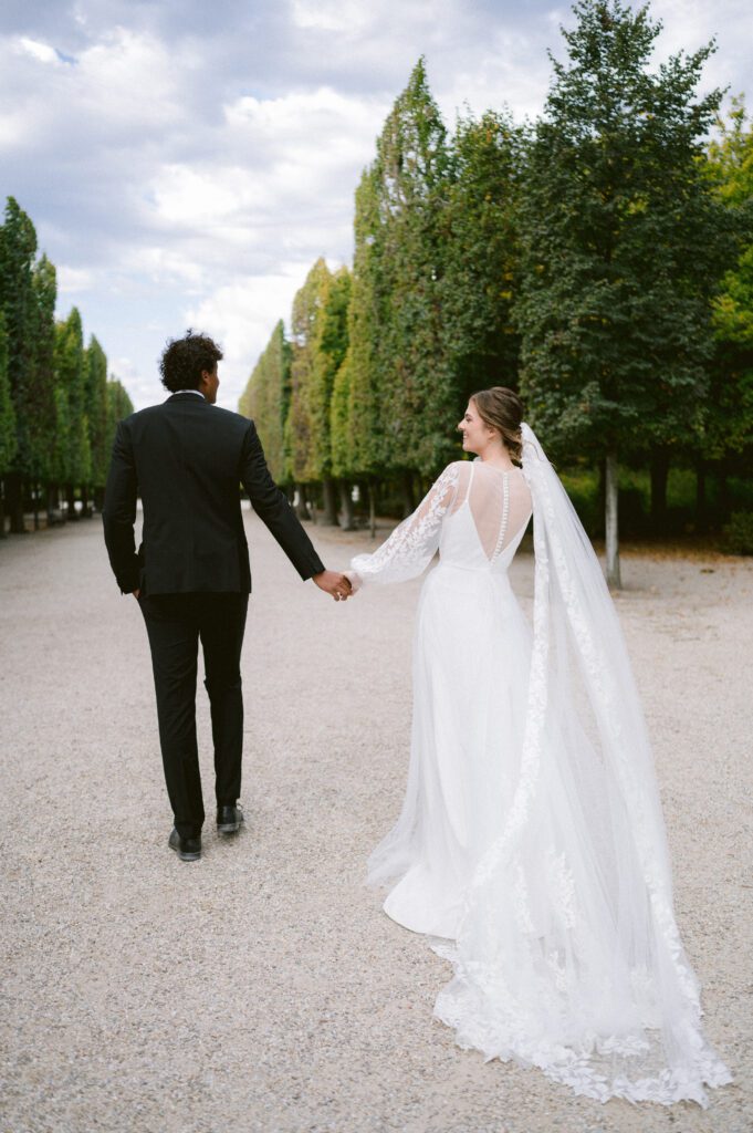 Bride and groom walking hand in hand outdoors at Schoenbrunn Palace Vienna wedding