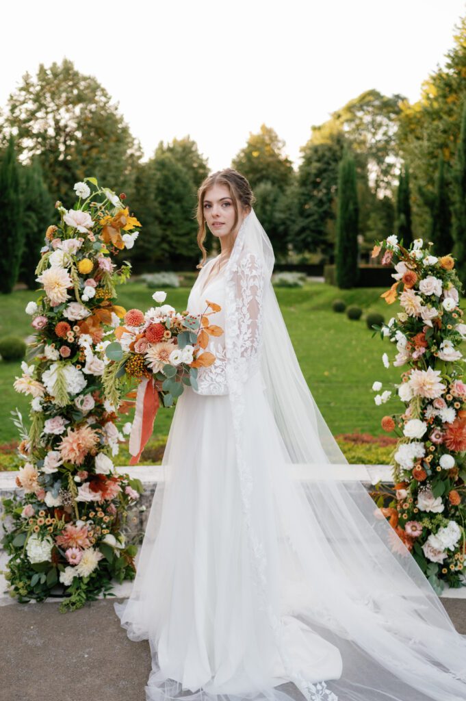 A portrait of the bride holding her bouquet in front of florals at Schoenbrunn Palace Vienna wedding