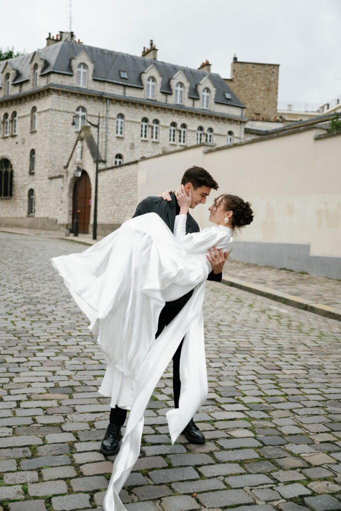 Bride and groom portrait of groom holding bride in his arms during Montmartre Paris wedding